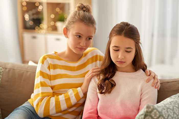 A girl comforts another girl, highlighting the emotional distress related to a wife not becoming a caregiver for an orphaned nephew. A girl comforts another girl, highlighting the emotional distress related to a wife not becoming a caregiver for an orphaned nephew.