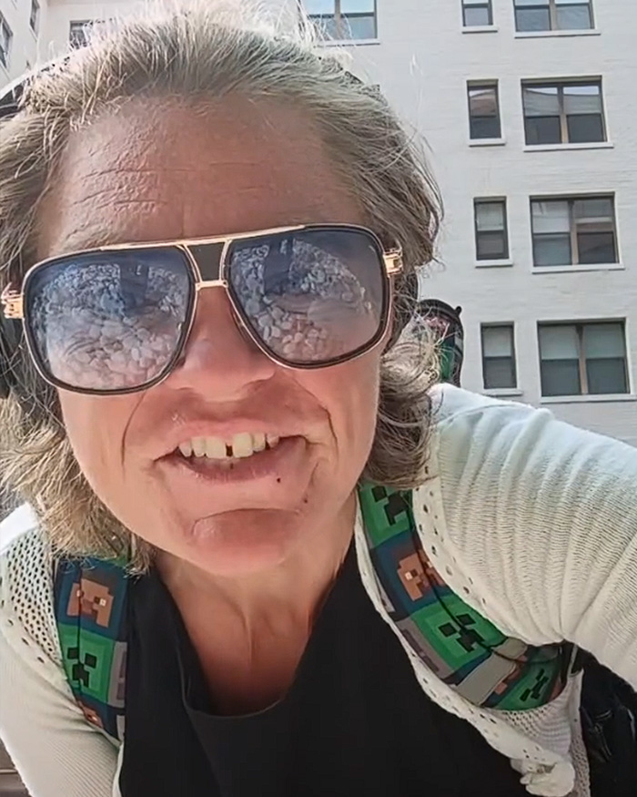 Close-up of a woman in sunglasses vandalizing WWII Memorial, sparking fury for defacing the memorial.