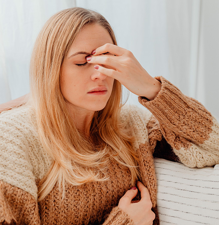 Woman suffering discomfort and touching forehead due to odd scalp pulling sensations Woman suffering discomfort and touching forehead due to odd scalp pulling sensations