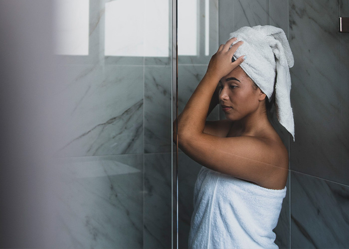 Woman in a towel after showering at home, experiencing pulling sensations in scalp. Woman in a towel after showering at home, experiencing pulling sensations in scalp.