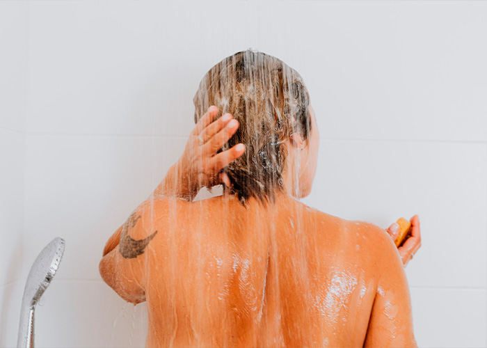Person washing hair in shower with scalp pulling sensations after home showering Person washing hair in shower with scalp pulling sensations after home showering