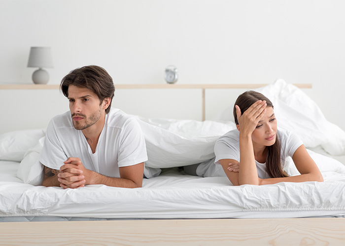 A man and woman in bed, looking away from each other, appearing distant. An instant mood killer is a common question men ask. A man and woman in bed, looking away from each other, appearing distant. An instant mood killer is a common question men ask.