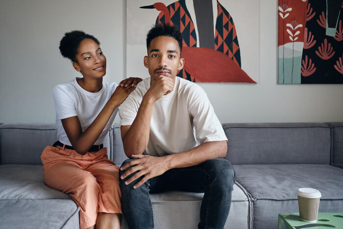 A woman with her hand on a man's shoulder, who looks pensive, perhaps considering an escape from comments from women.