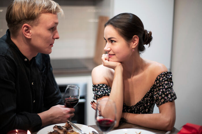 A couple having a date night with wine and food, discussing their date nights or possible escape.
