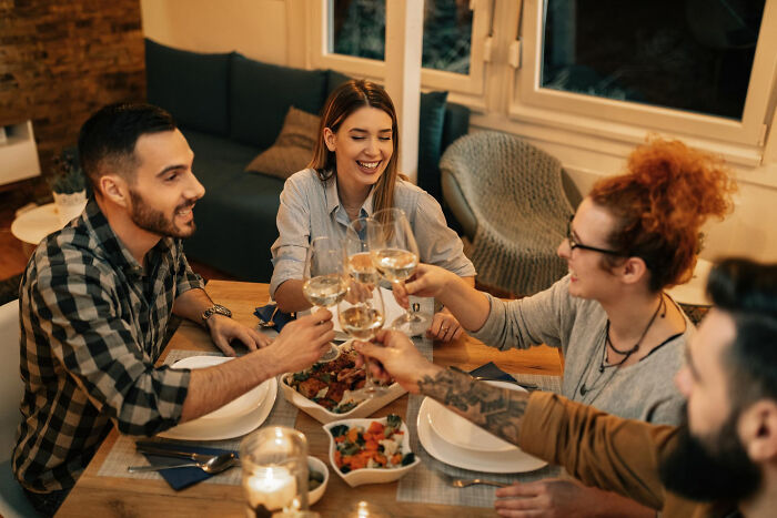 Friends toasting during a dinner, enjoying their evening, contrasting with comments that made men plan their escape.
