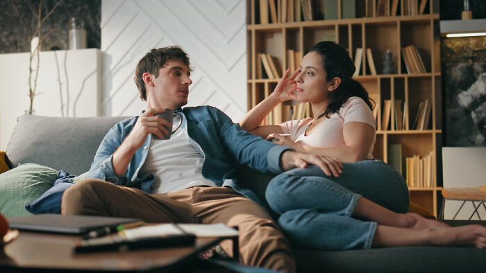 A couple on a couch, deep in conversation, possibly about women's comments impacting date nights.