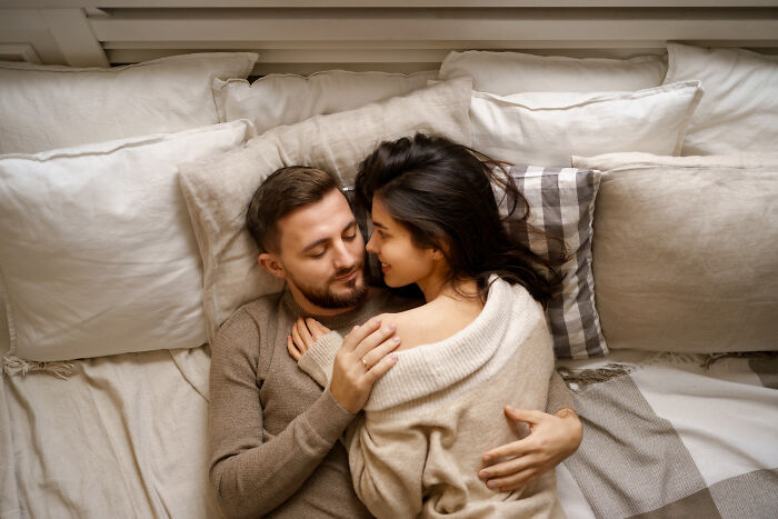 A happy couple cuddling in bed, representing date nights and the intimacy women desire.