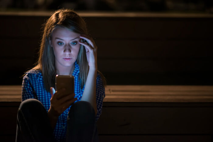 A distressed woman looking at her phone, possibly reacting to comments from women that made men plan their escape.