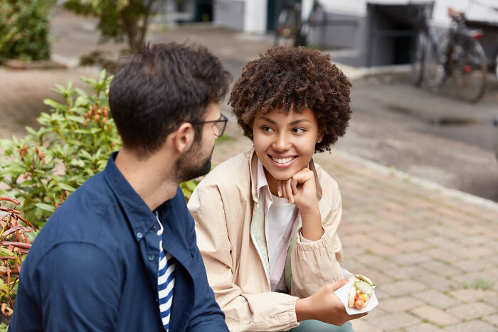 A woman with curly hair smiling at a man, illustrating interactions that might lead men to plan their escape.