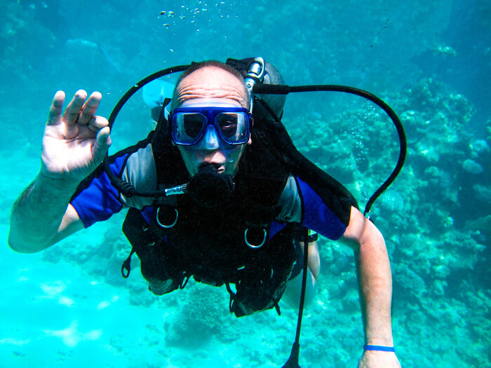 A man scuba diving, giving an OK gesture. Men planning their escape from date nights.