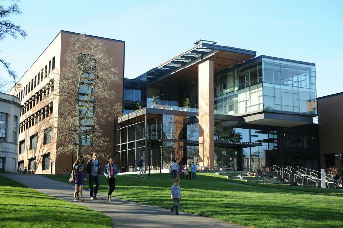 Students walk on a path outside a modern college building, embracing the new world of college life.