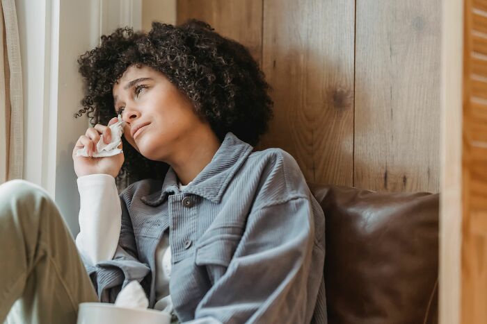 Woman with curly hair crying, holding a tissue, thinking about the worst things before walking away.