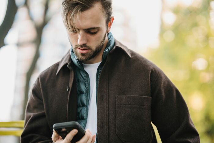 A man looking intently at his phone, depicting situations women put up with before walking away.