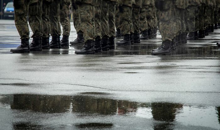 Soldiers in camouflage uniforms and boots stand in formation on a wet surface, symbolizing the worst things people put up with.
