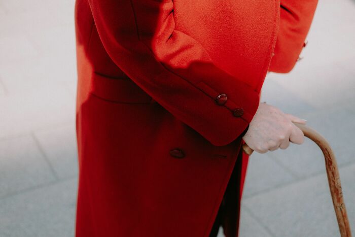 Close-up of a person in a red coat holding a cane. Women share what they put up with before walking away.