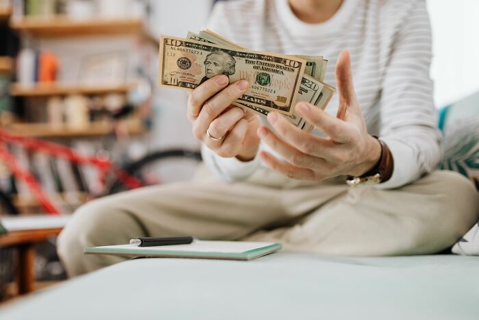 Hands holding US dollar bills, representing issues women face before finally walking away.