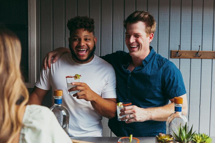 Two happy men share drinks and laughter, unaware of the worst things women put up with before walking away.