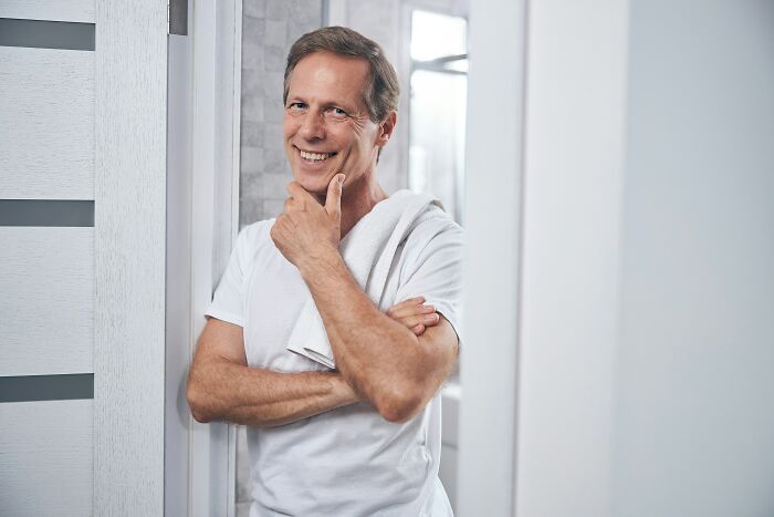 A man with a white shirt and towel smiles, reflecting on the worst things women put up with before walking away.