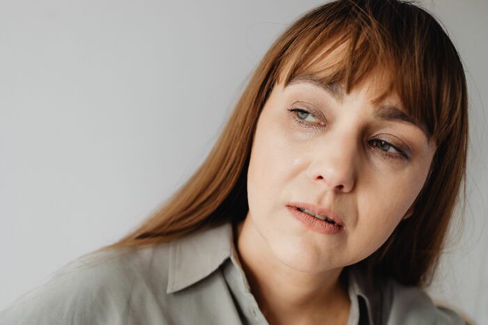 A woman with tears in her eyes, sad about a young and dumb decision that keeps her up at 3 AM.