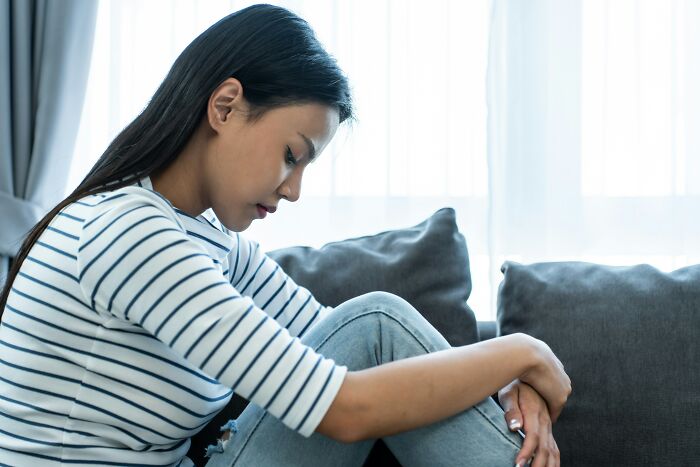A woman sits alone, looking sad, contemplating a young and dumb decision.