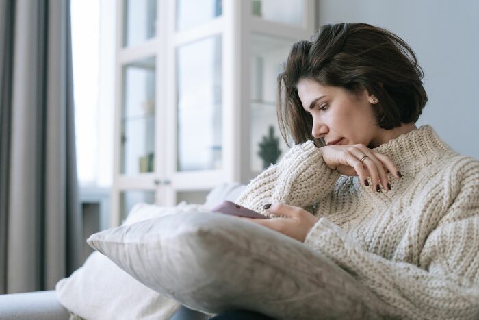 A woman looking at her phone, reflecting on a young and dumb decision that keeps her up at 3 AM.
