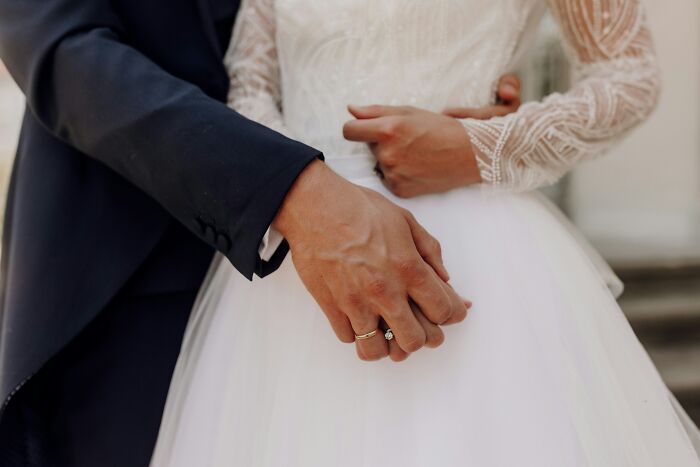 A couple's hands with a wedding ring, symbolizing a young and dumb decision in relationships.