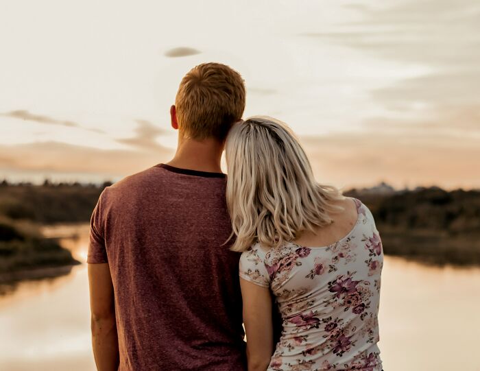 A woman rests her head on a man's shoulder, reflecting on a young and dumb decision.