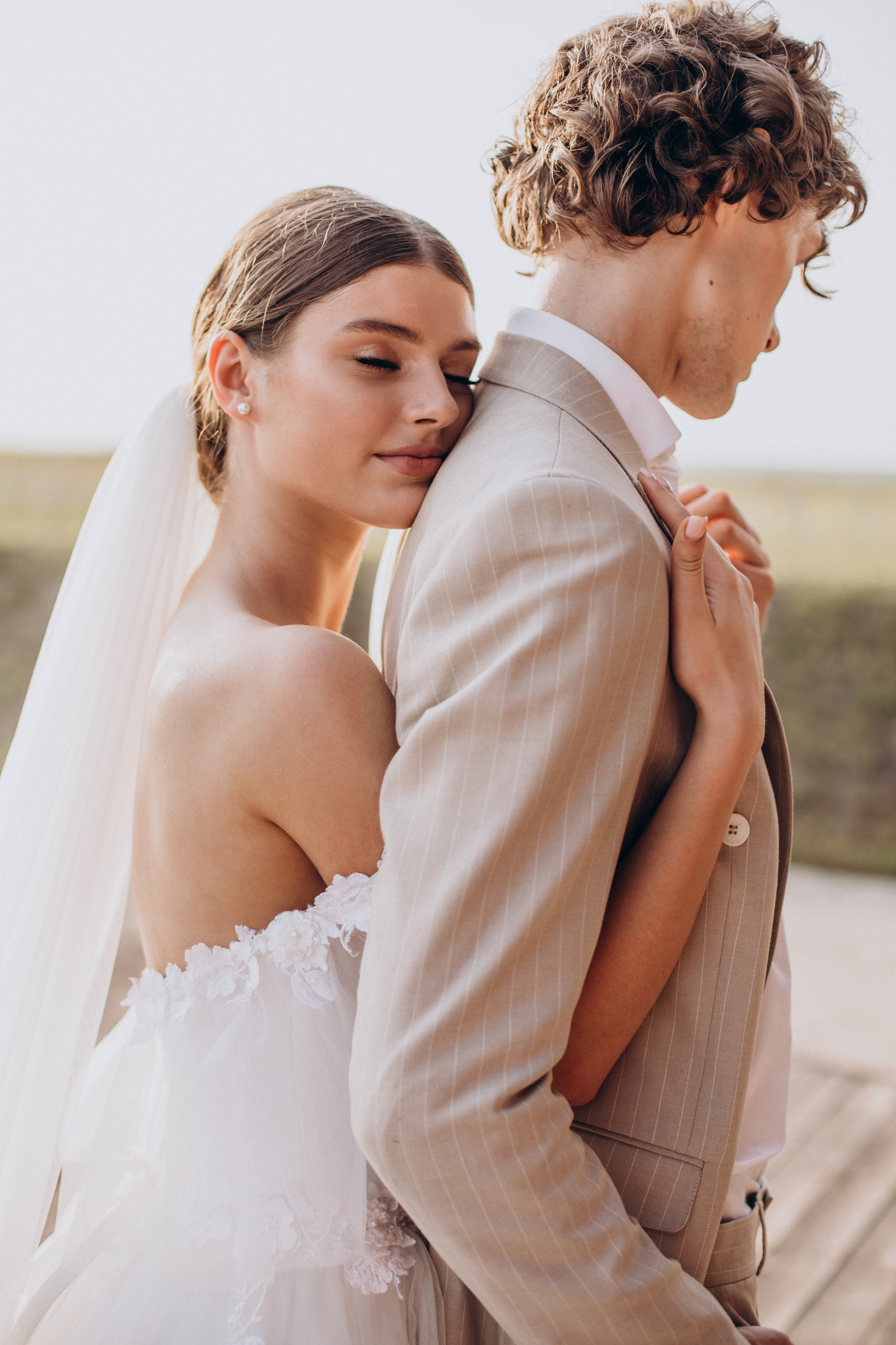 A beautiful bride in a white strapless gown hugs her groom in a tan suit, showing a loving moment amidst wedding dispute discussion. A beautiful bride in a white strapless gown hugs her groom in a tan suit, showing a loving moment amidst wedding dispute discussion.
