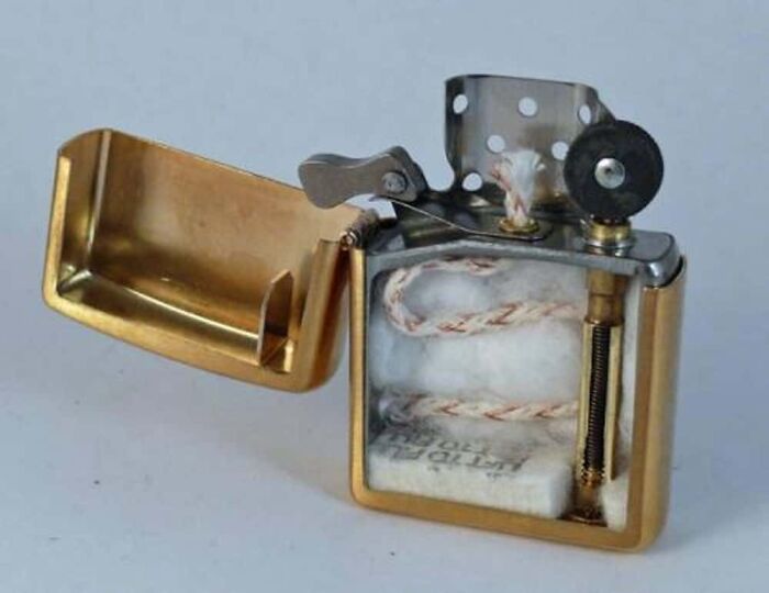 A gold Zippo lighter cut in half, showing the wick, cotton, and spring inside, a surprising photo of an object cut in half.