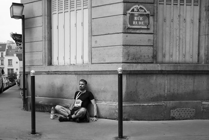 Perfectly timed street photo by Gaspard Claude showing an unseen side of Paris: a man sitting on a street.