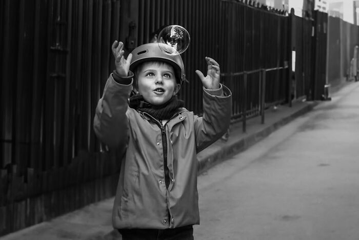 Perfectly timed street photo by Gaspard Claude illustrating an unseen side of Paris: a boy playing with a bubble.