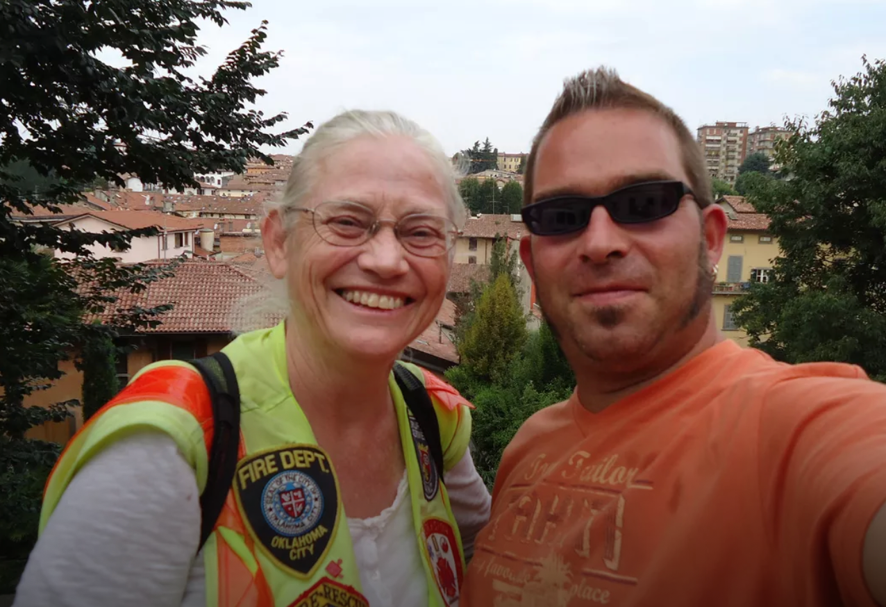 Smiling woman in fire dept vest with man outdoors in leukemia survival story Smiling woman in fire dept vest with man outdoors in leukemia survival story
