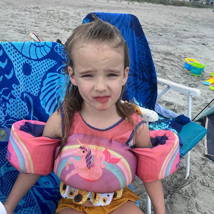 A photo of Saylor Hayes as a 5-year-old child, sitting on a beach chair, wearing a swim vest, reflecting the disturbing details.