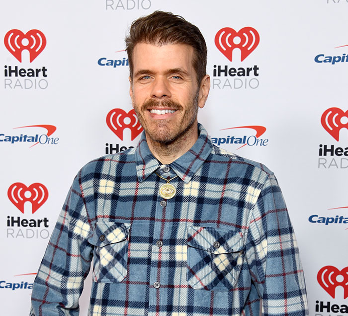 Perez Hilton, smiling at an event, with his family launching GoFundMe to help raise his kids amid disfigurement reports.