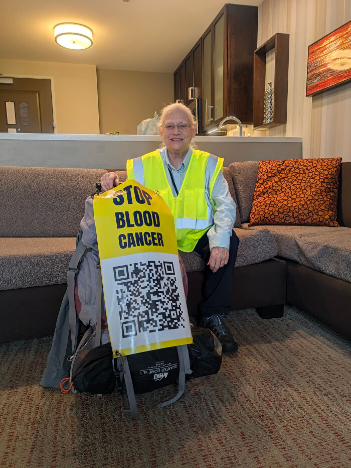 Woman in safety vest with backpack displaying stop blood cancer sign Woman in safety vest with backpack displaying stop blood cancer sign