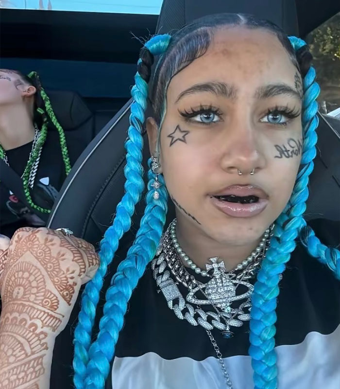 North West at 13, with blue braids, face tattoos, and heavy jewelry, central to parenting controversy.