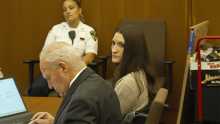 Lindsay Clancy, in court, looks over her shoulder, with a male attorney and a female officer also present. Lindsay Clancy, in court, looks over her shoulder, with a male attorney and a female officer also present.