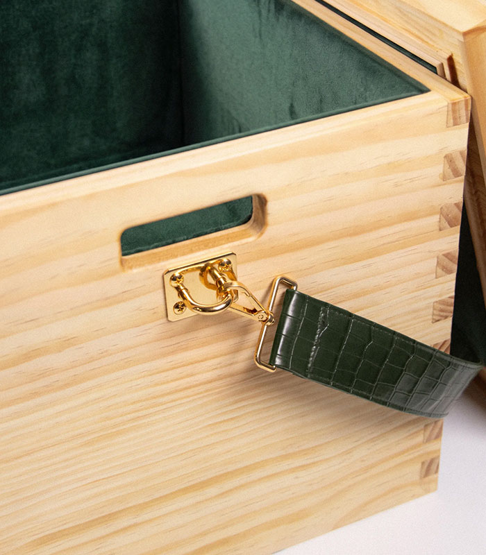 Close-up of the Beyoncé wooden box showing its dark green interior, a gold clasp, and a green strap. Close-up of the Beyoncé wooden box showing its dark green interior, a gold clasp, and a green strap.
