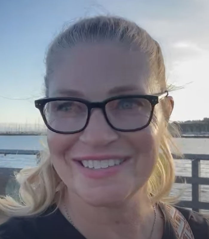 The Racist Karen smiling, with a pier and water in the background. The Racist Karen smiling, with a pier and water in the background.
