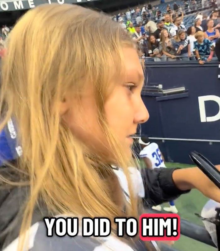 A young kid with blonde hair looking upset at a stadium after an NFL hat incident A young kid with blonde hair looking upset at a stadium after an NFL hat incident