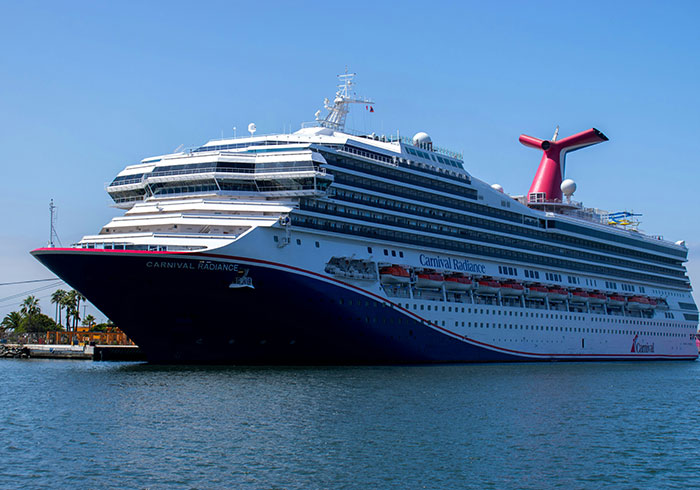 The large Carnival Radiance cruise ship travels on the blue ocean under a clear sky