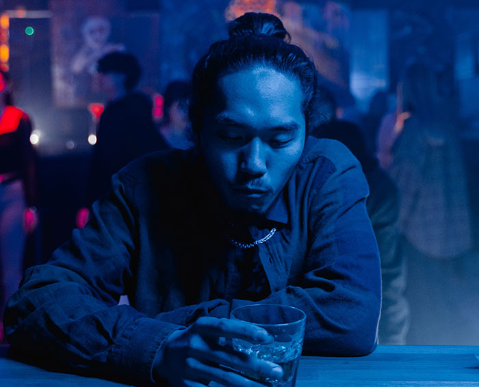 A man looking down at his drink in a dimly lit bar, showcasing dating mistakes before a meetup. A man looking down at his drink in a dimly lit bar, showcasing dating mistakes before a meetup.