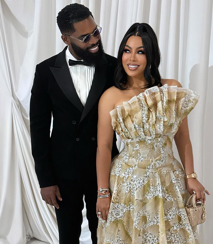 Influencer in a tuxedo with a woman in an elegant gown, after male cosmetic procedure, looking at each other.