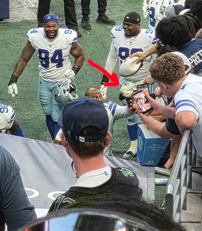 An NFL player hands over an NFL hat to a young fan at a match. An NFL player hands over an NFL hat to a young fan at a match.