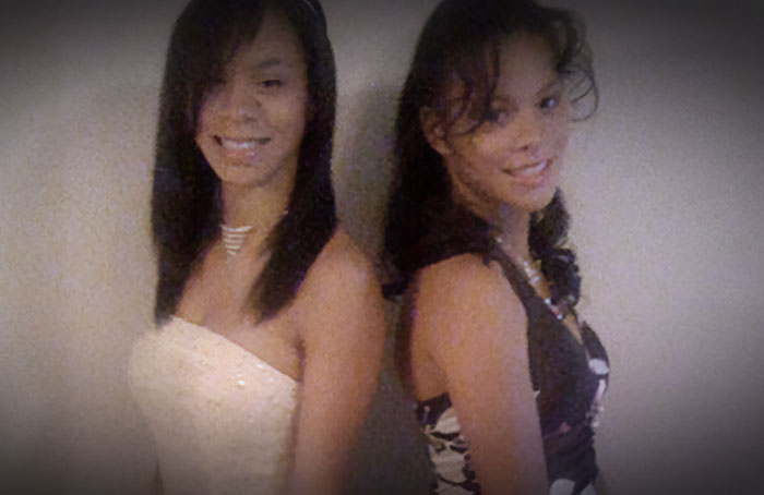 Two teenage twins dressed up and posing back-to-back at an event Two teenage twins dressed up and posing back-to-back at an event