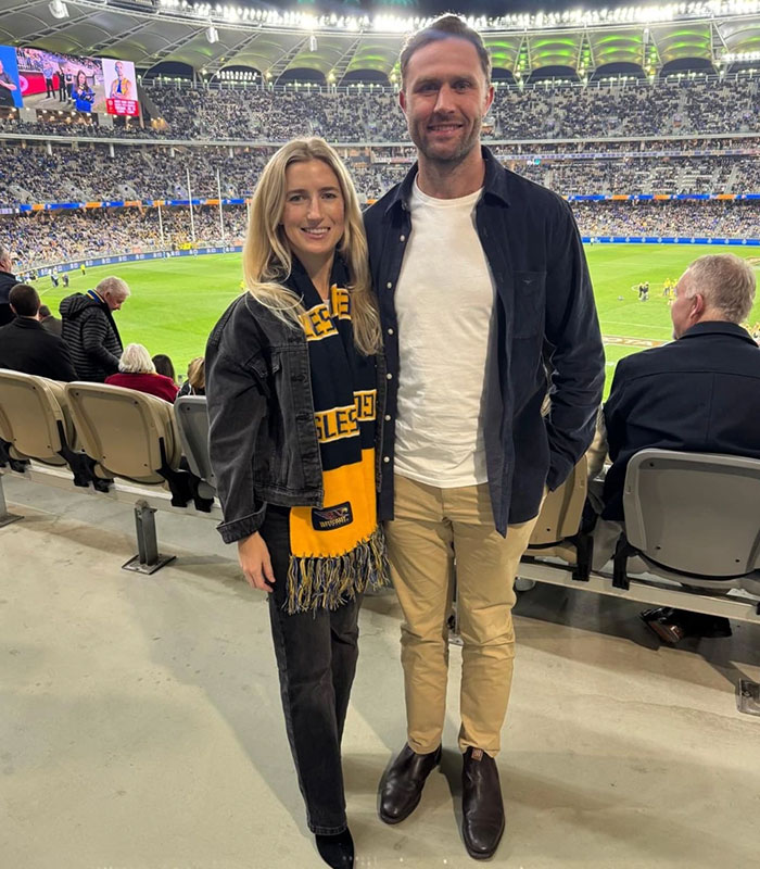 Star athlete and wife wearing team scarf at a packed sports stadium
