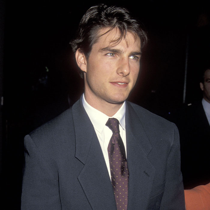 A young Tom Cruise smiling while wearing a suit and tie A young Tom Cruise smiling while wearing a suit and tie