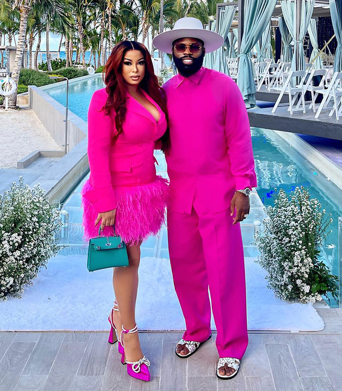 Influencer in a bright pink suit and hat with a woman in a pink feathered dress, after male cosmetic procedure.