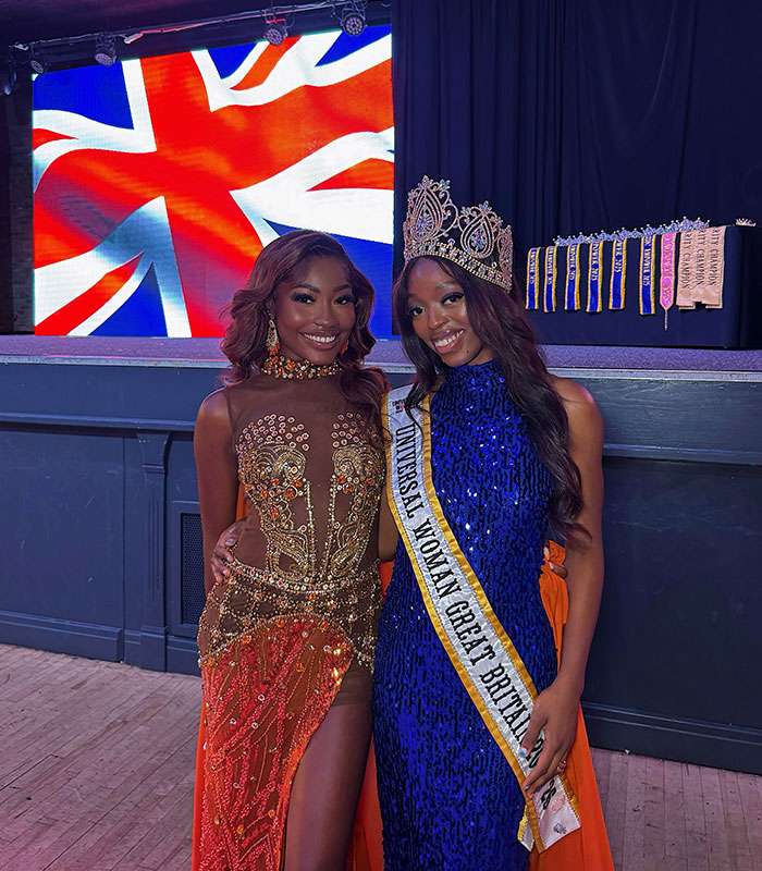 Two women in elegant dresses with a British flag backdrop, one being the Universal Woman 2026 choice. Two women in elegant dresses with a British flag backdrop, one being the Universal Woman 2026 choice.