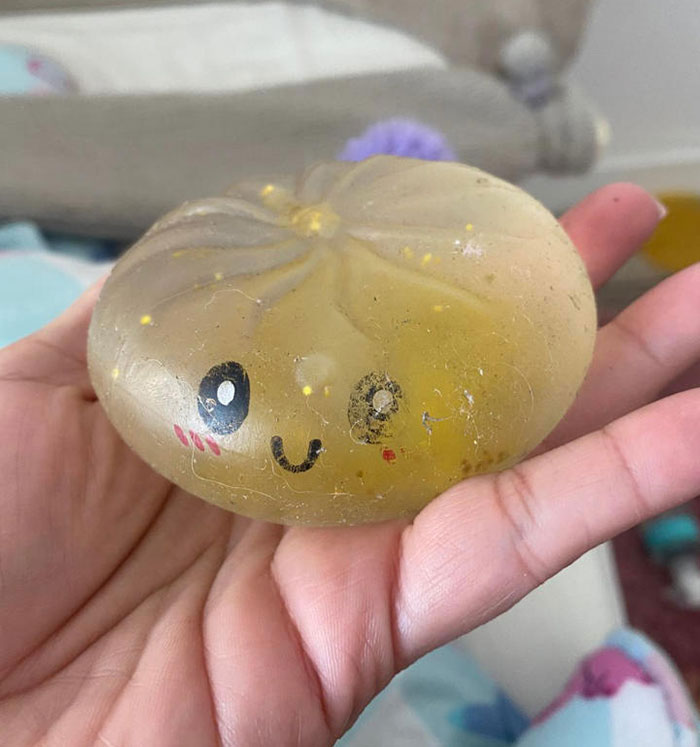 A hand holding a clear, glittery squishy toy shaped like a bun with a small smiling face, emphasizing popular squishy toys. A hand holding a clear, glittery squishy toy shaped like a bun with a small smiling face, emphasizing popular squishy toys.